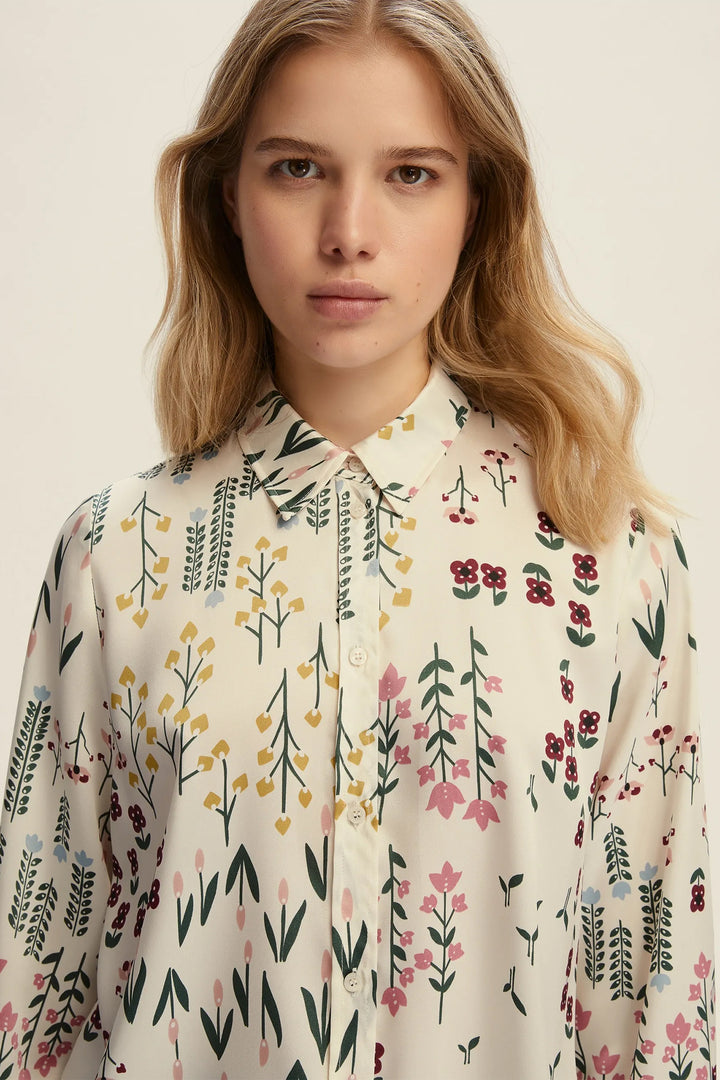 Woman wearing a floral patterned shirt against a plain background