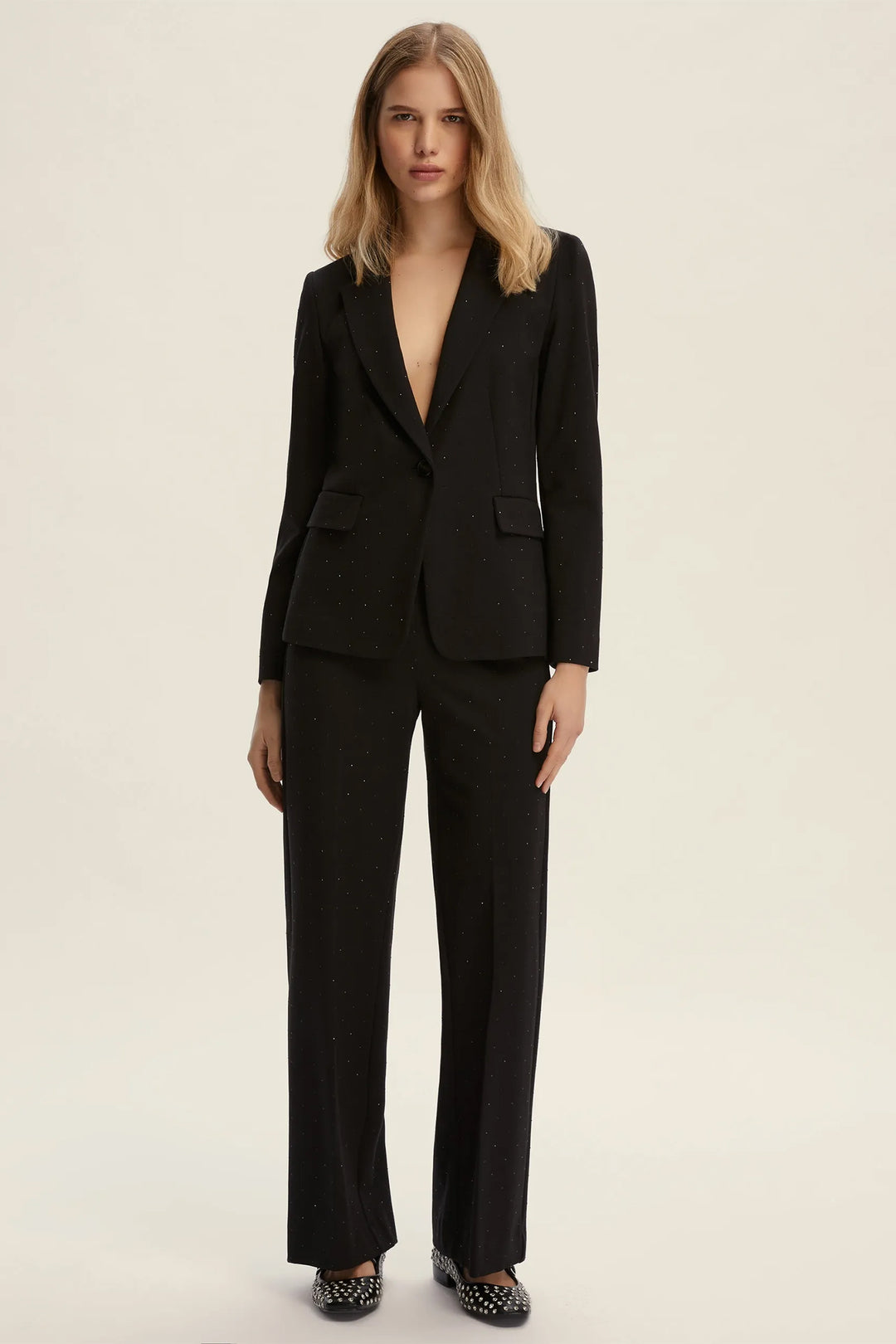 Woman wearing a black suit on a beige background