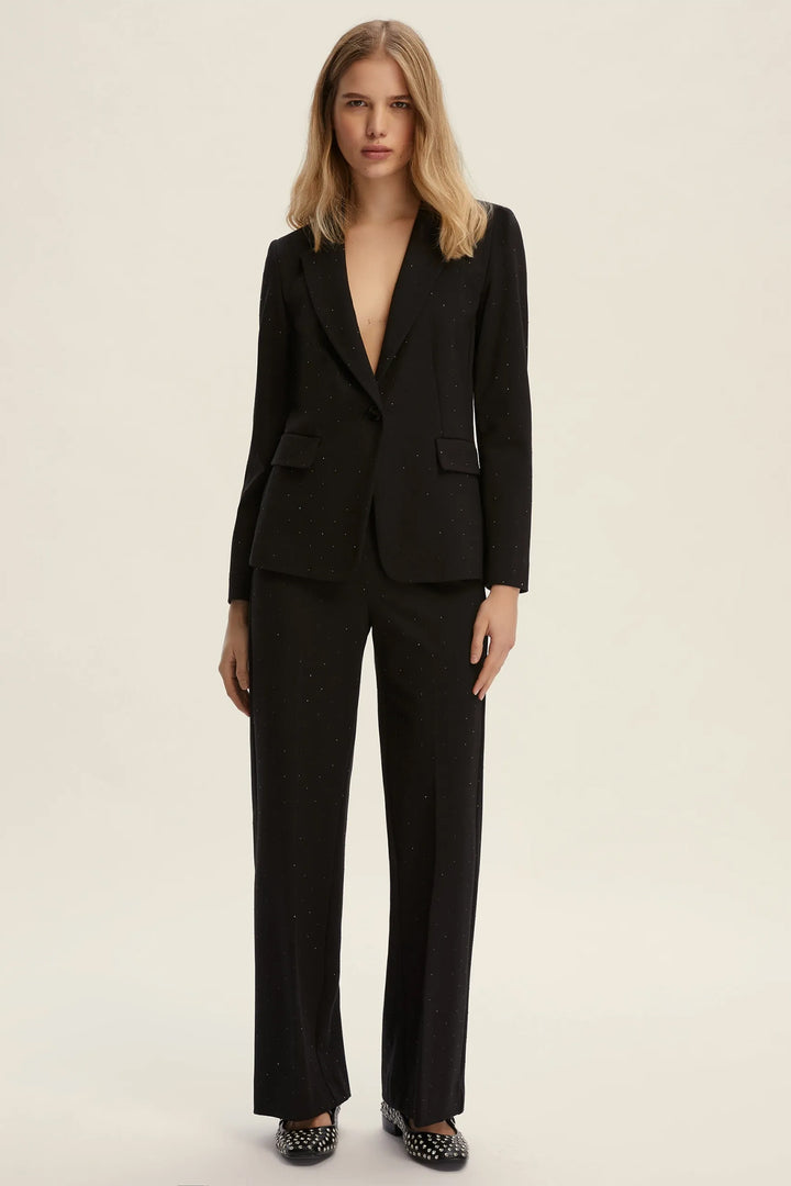 Woman wearing a black suit on a beige background