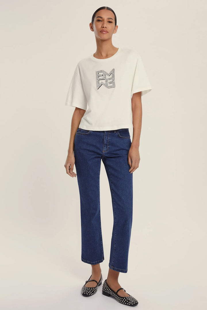 Woman wearing a white t-shirt with text and blue jeans on a plain background