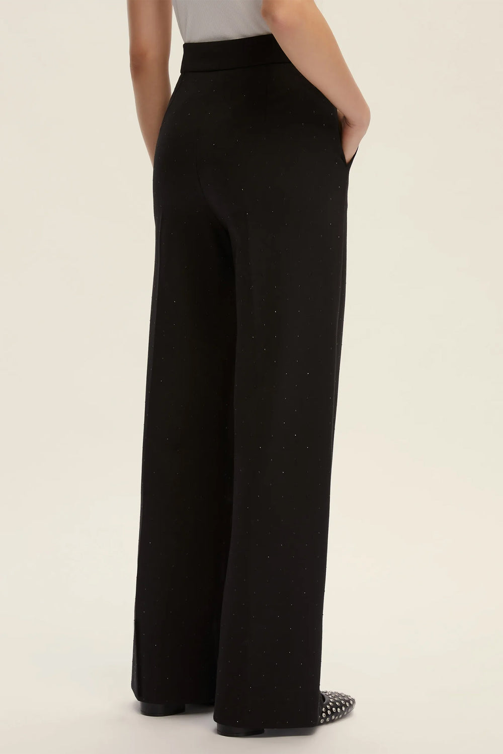 Person wearing black wide-leg pants on a plain background