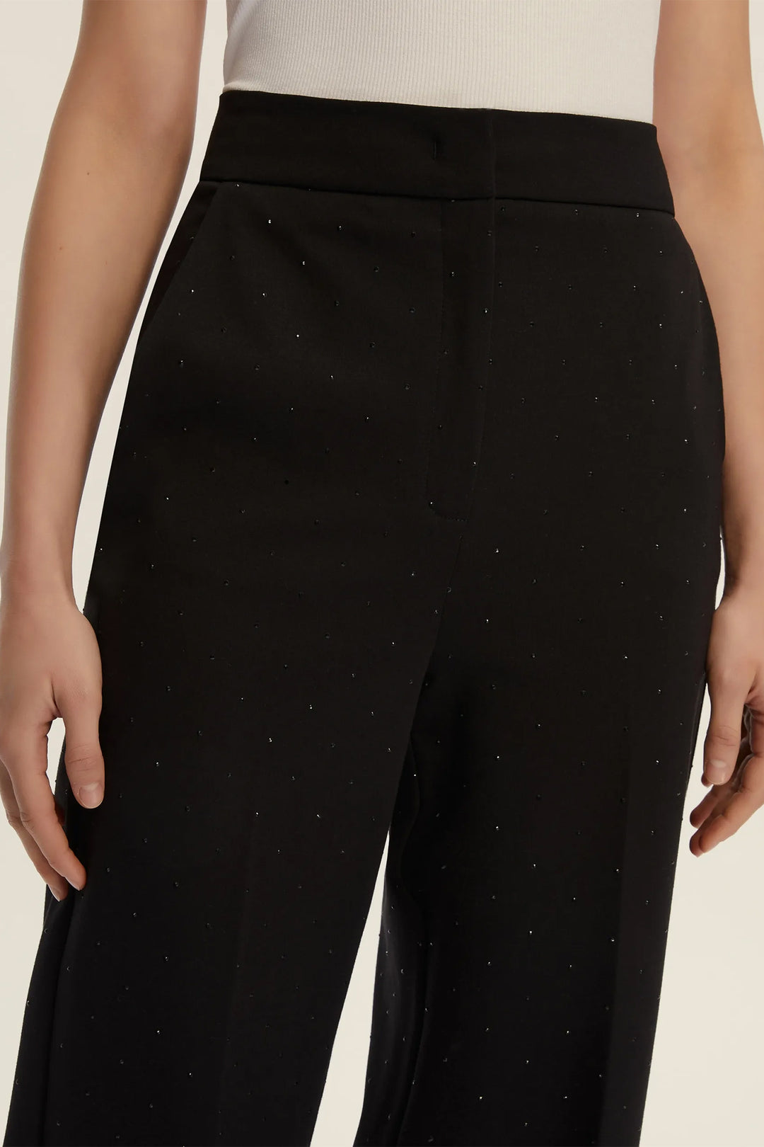 Black pants with a subtle pattern worn by a person on a neutral background