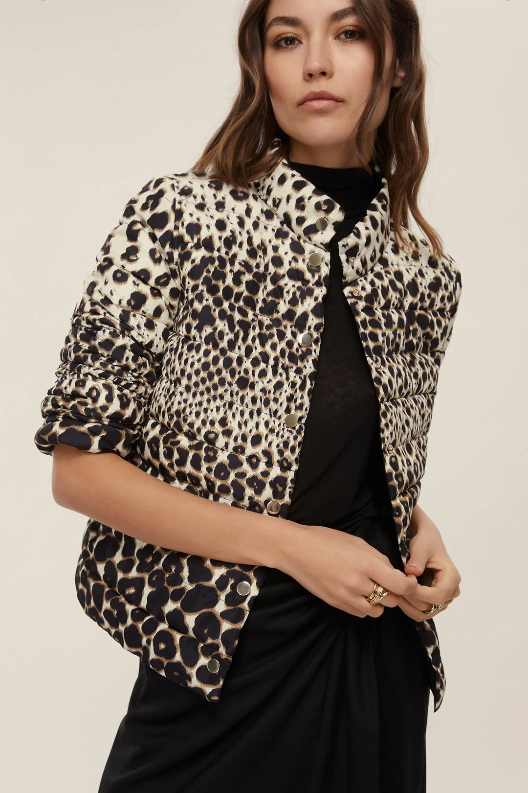 Woman wearing a leopard print jacket over a black top on a beige background