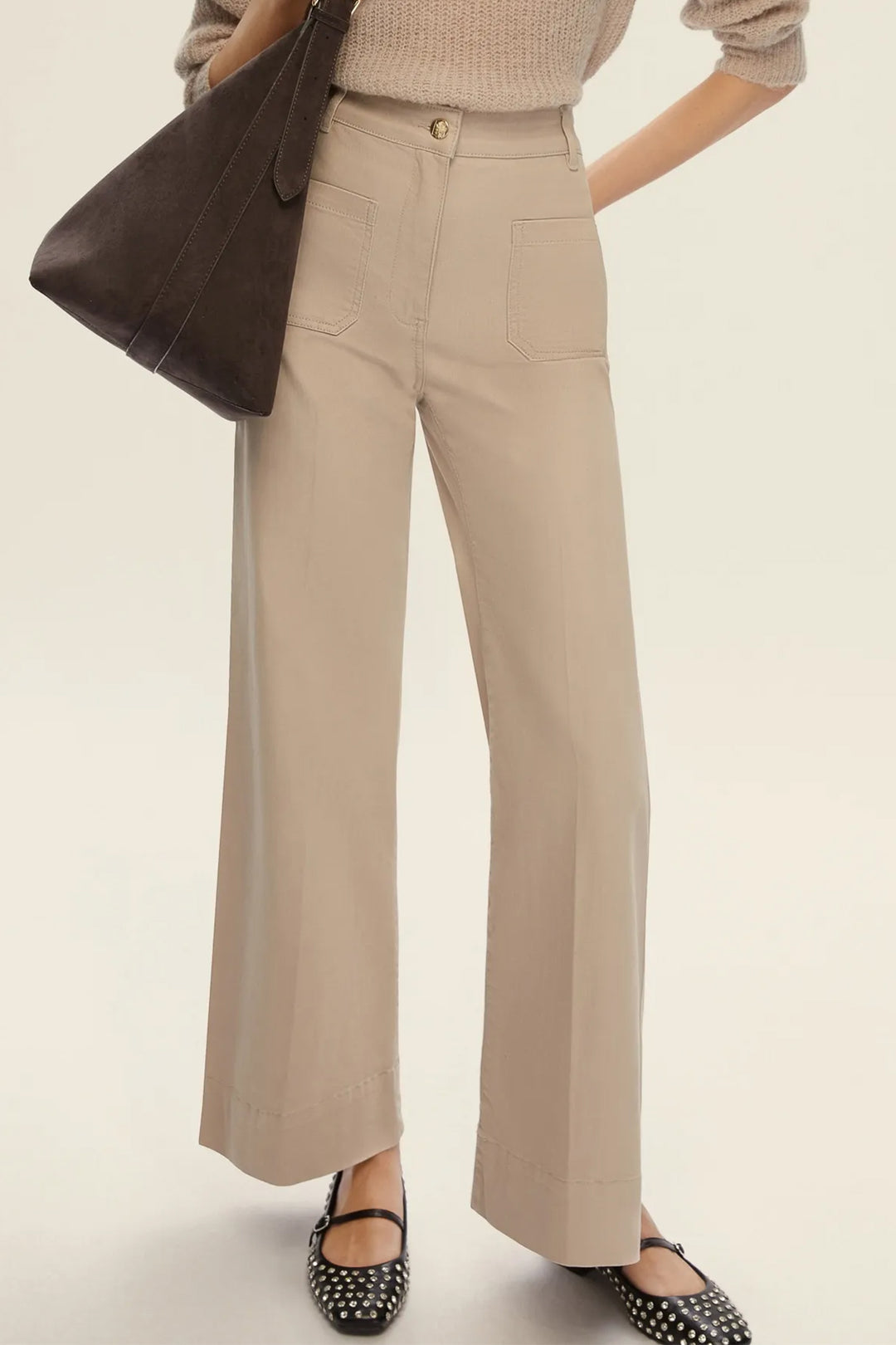 Person wearing beige pants with a brown bag on a light background