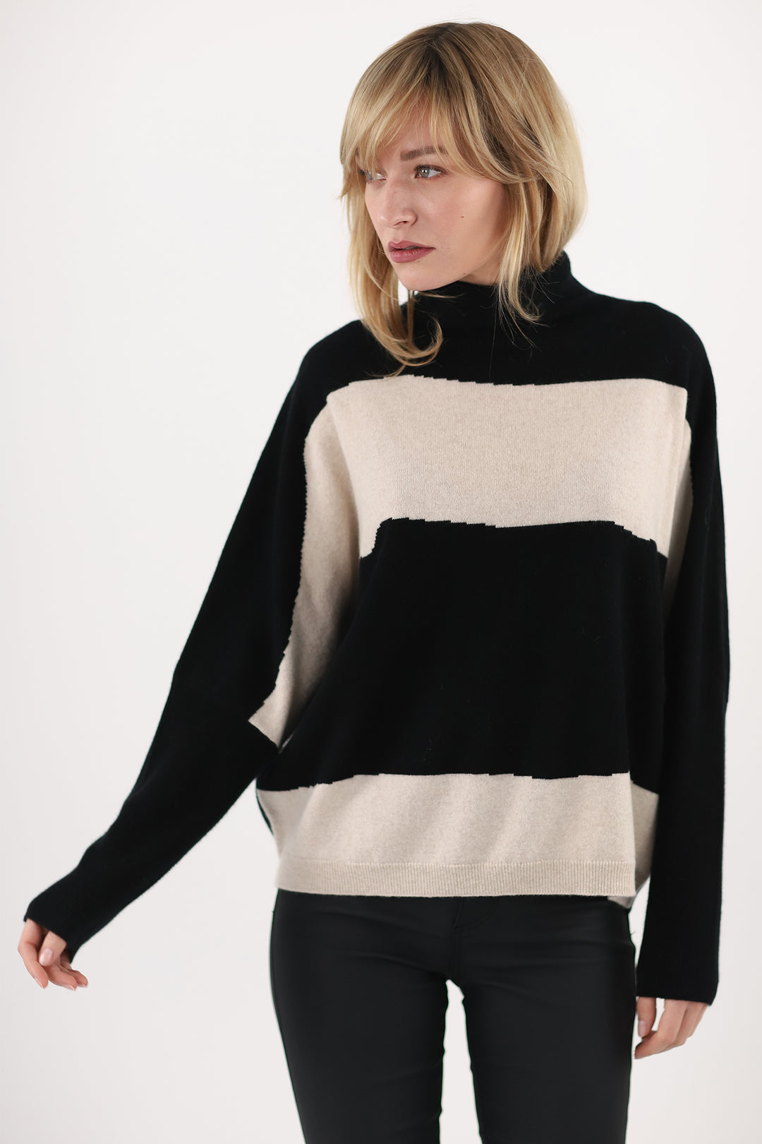 Woman wearing a black and beige color-blocked sweater on a white background