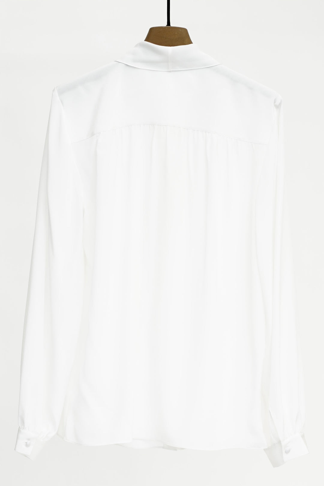 White shirt on a hanger against a white background