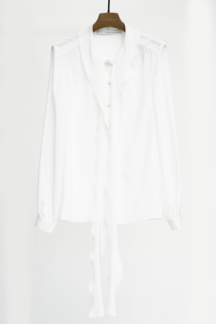 White shirt hanging on a wooden hanger against a white background