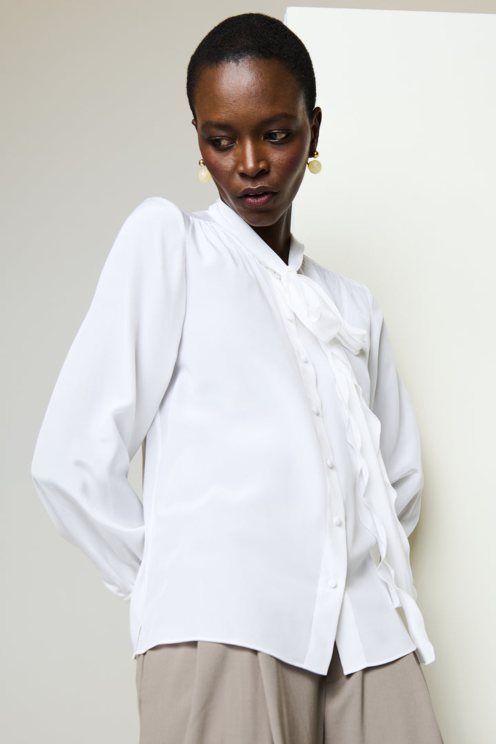 Woman wearing a white blouse with a plain background