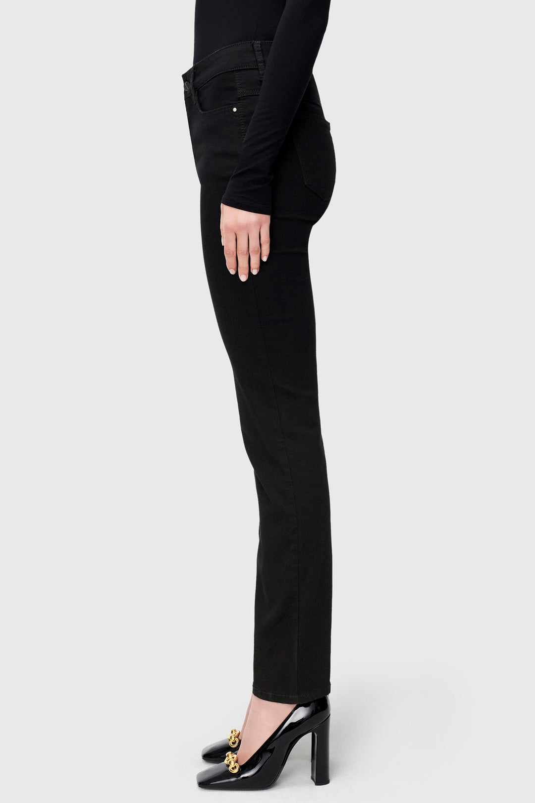 Person wearing black jeans and high heels on a white background