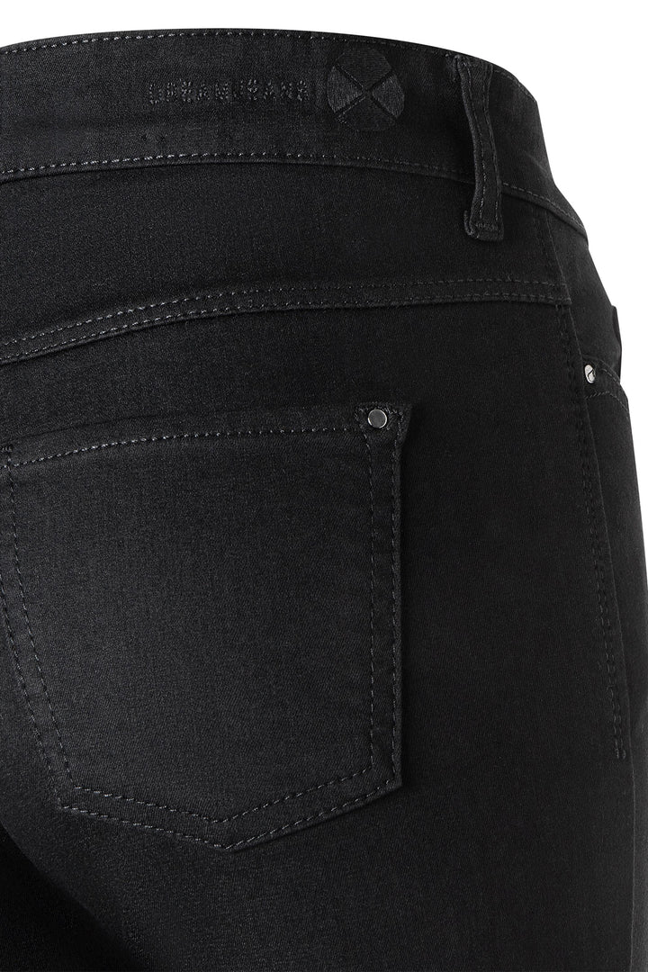 Close-up of black jeans with a visible brand label on a white background