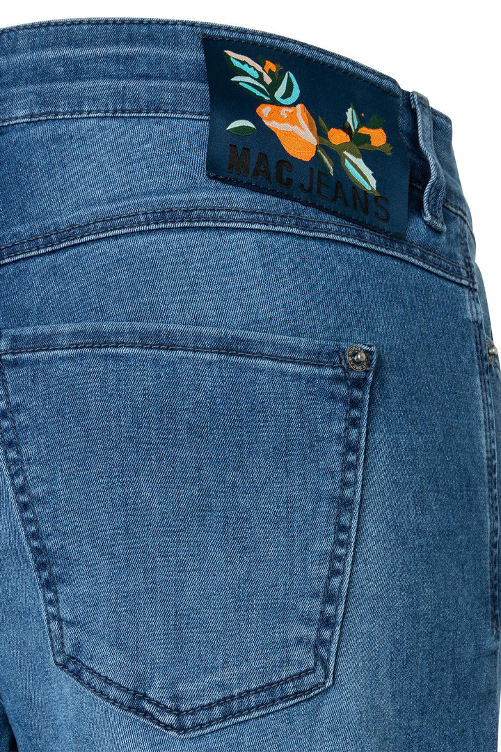 Close-up of blue jeans with a brand label featuring floral designs.