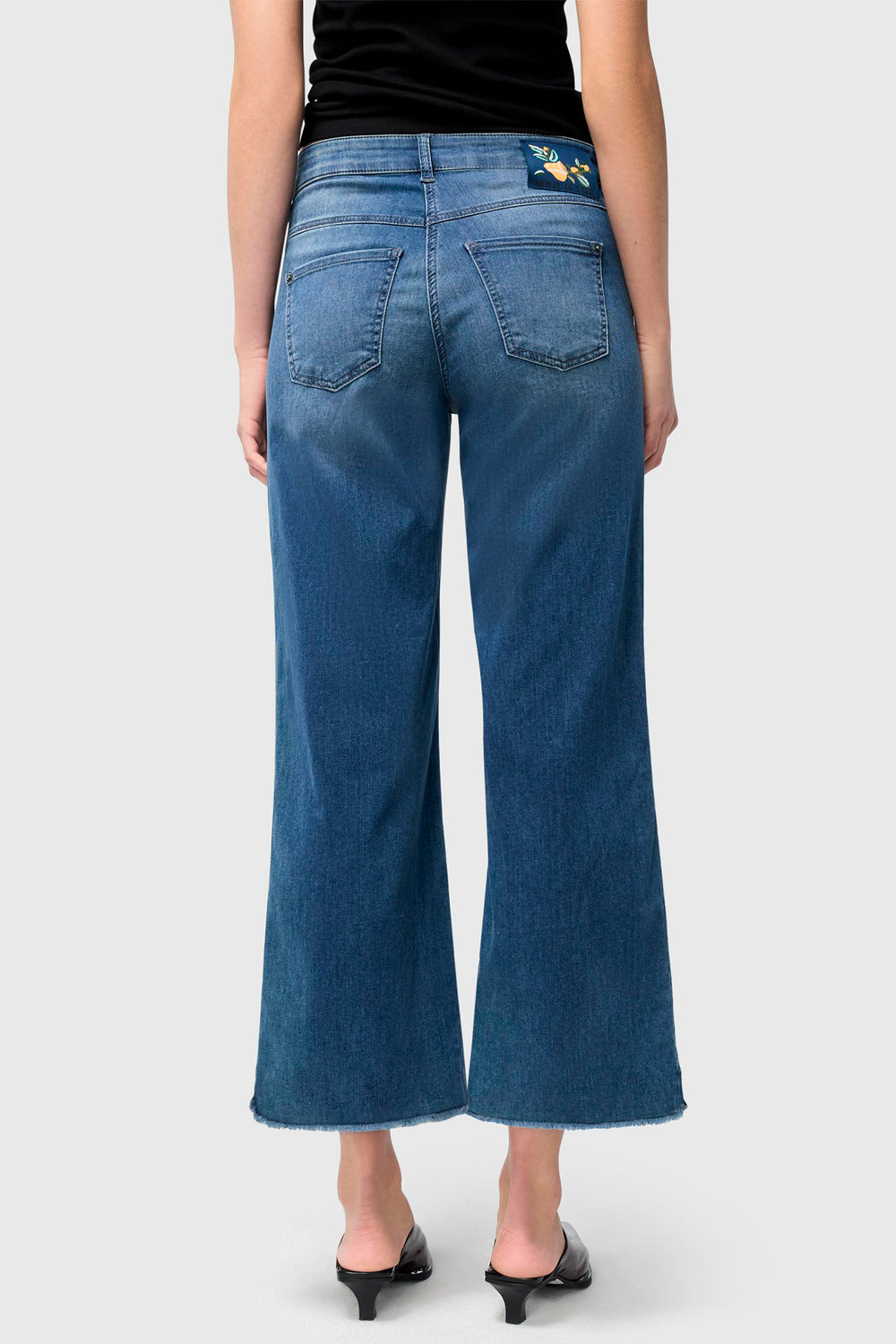 Person wearing blue jeans on a plain background