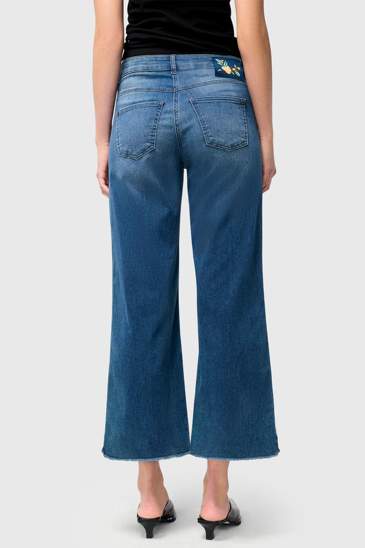 Person wearing blue jeans on a plain background