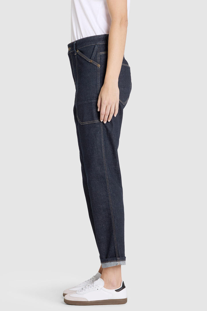 Person wearing dark blue jeans and white sneakers on a white background