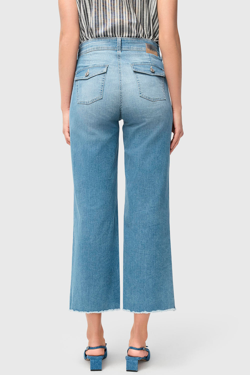 Person wearing light blue jeans on a plain background