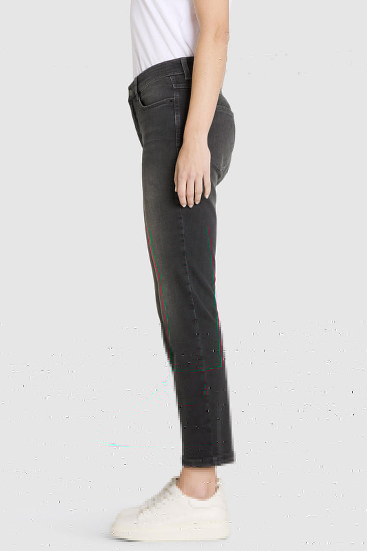 Person wearing black jeans and white sneakers on a light gray background