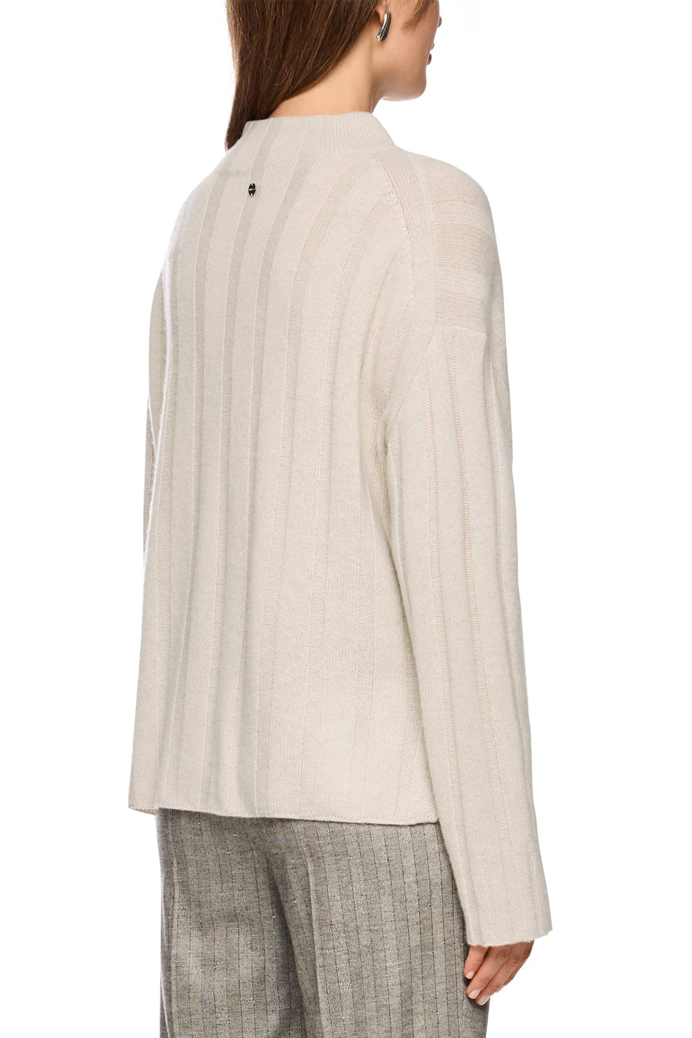 Woman wearing a beige long-sleeve top and gray plaid pants on a white background