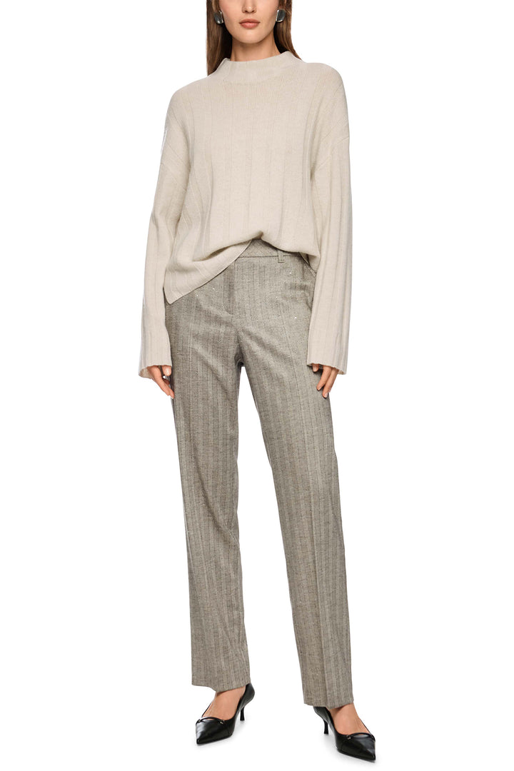 Woman wearing a beige sweater and plaid pants on a white background