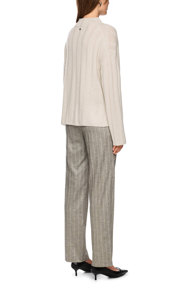 Woman wearing a beige blazer and plaid pants on a white background