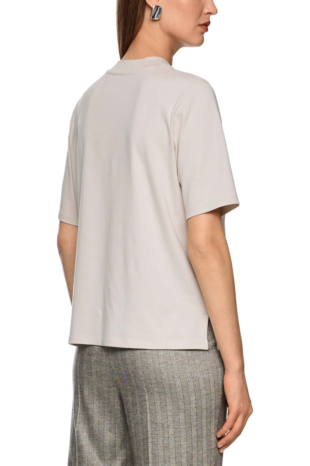 Woman wearing a beige short-sleeve top and plaid pants on a white background