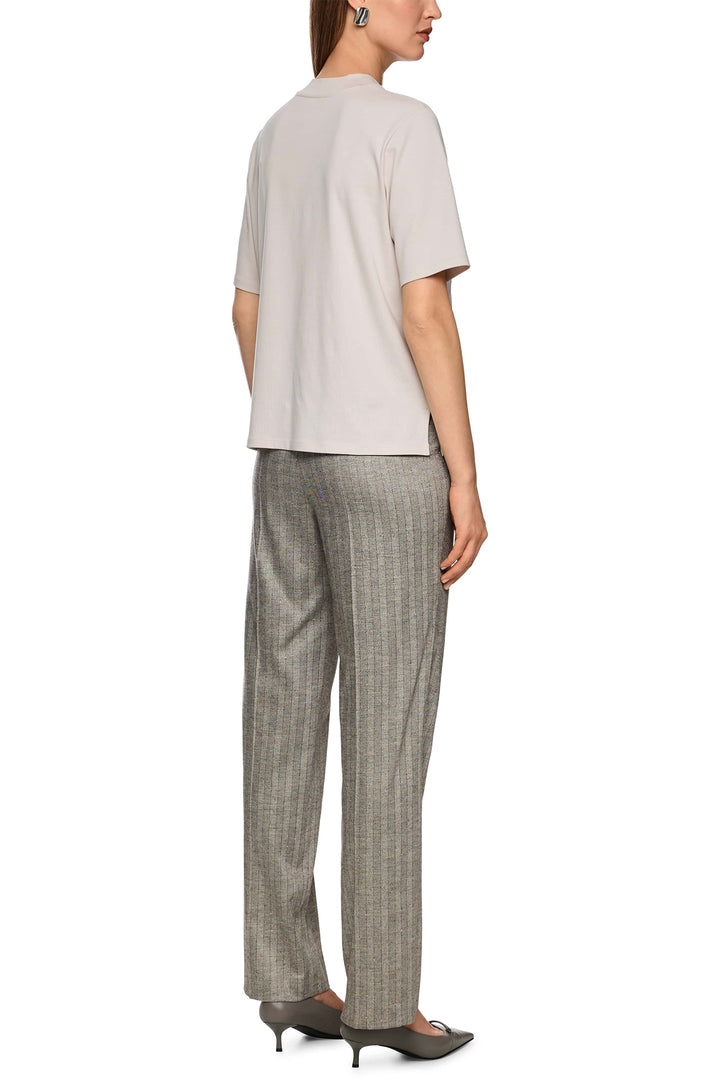 Woman wearing a beige top and checkered pants on a white background