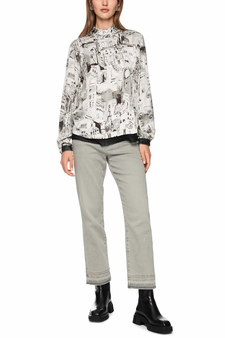 Person wearing a patterned blouse and light gray pants on a white background