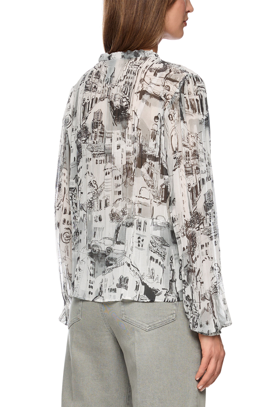 Woman wearing a patterned blouse with long sleeves on a white background