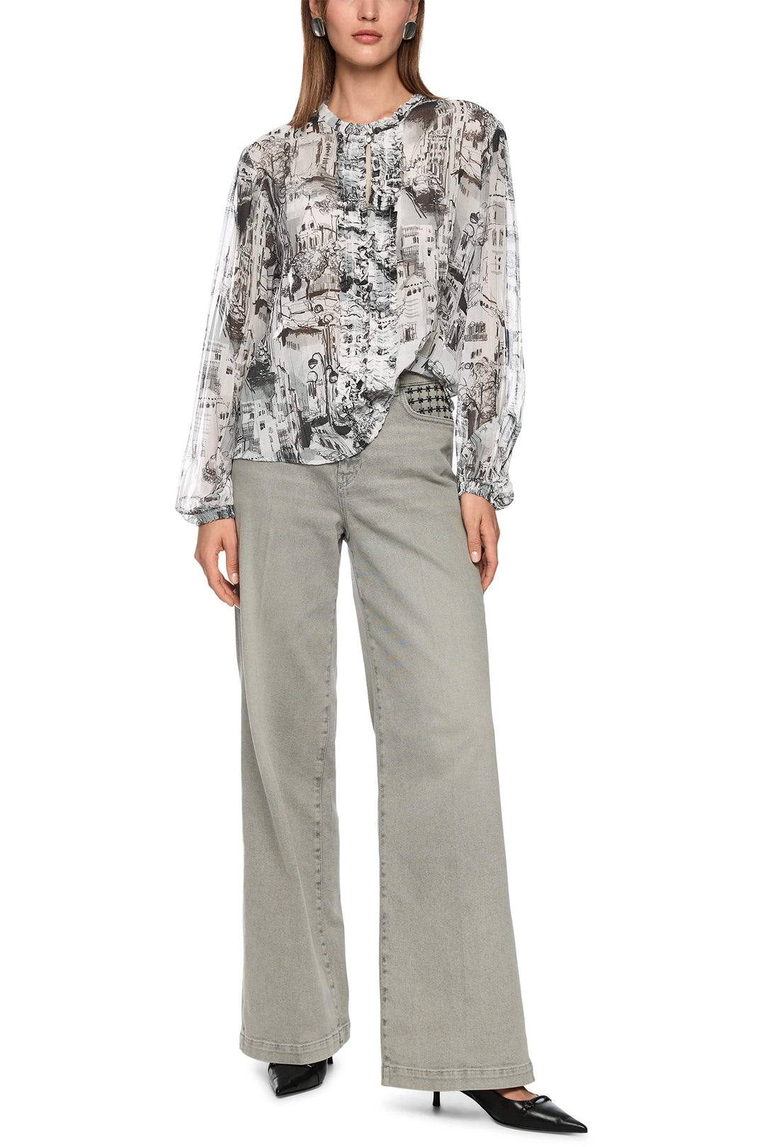 Woman wearing a patterned blouse and light gray pants on a white background