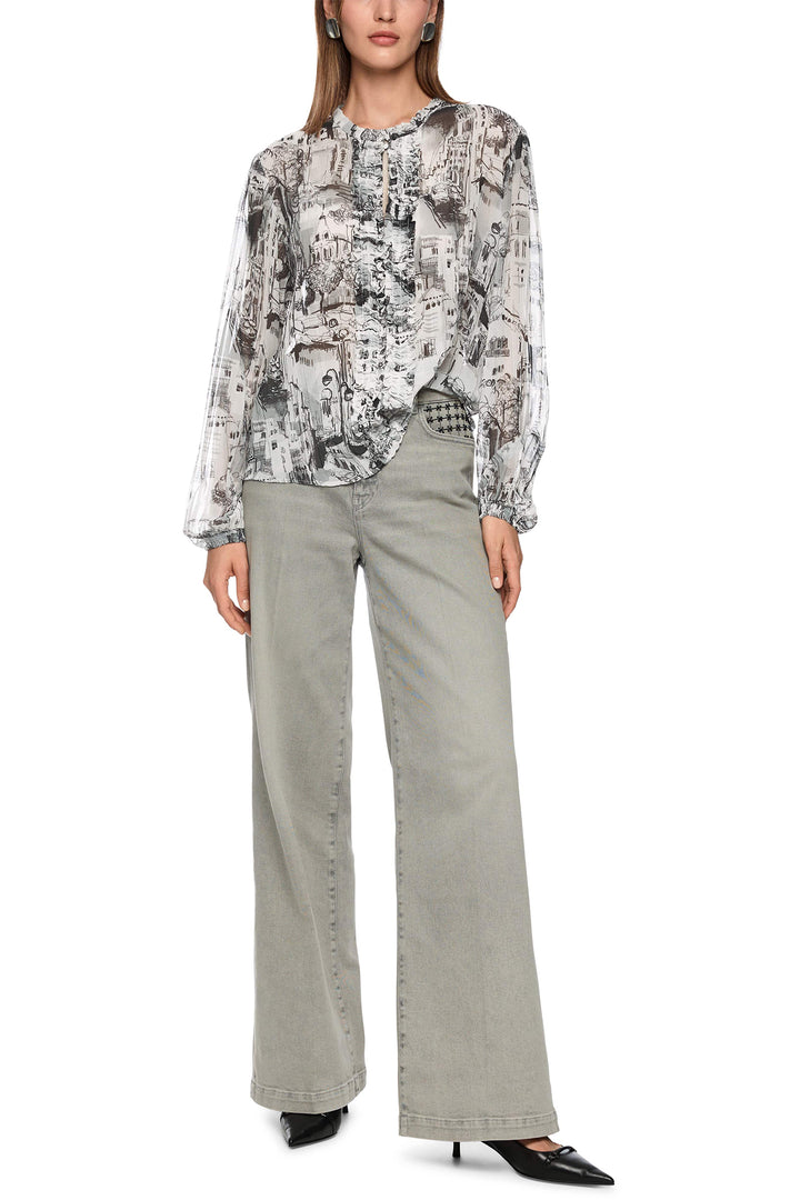 Woman wearing a patterned blouse and light gray pants on a white background