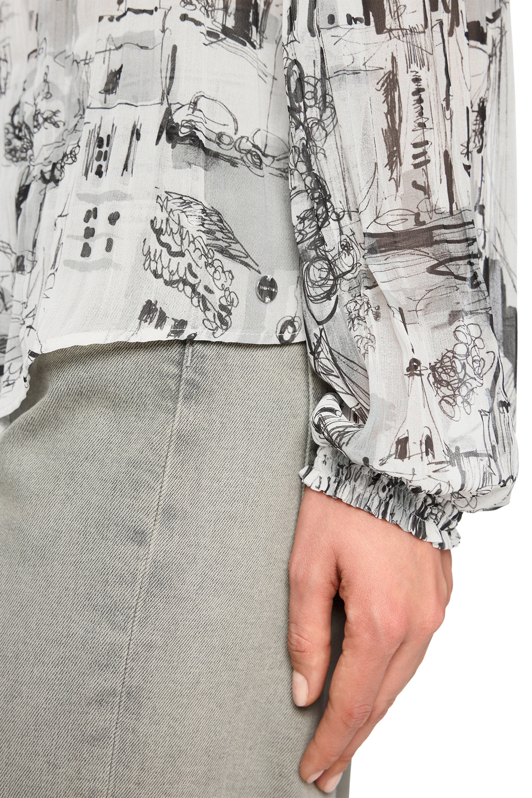 Close-up of a person wearing a patterned shirt and gray pants.