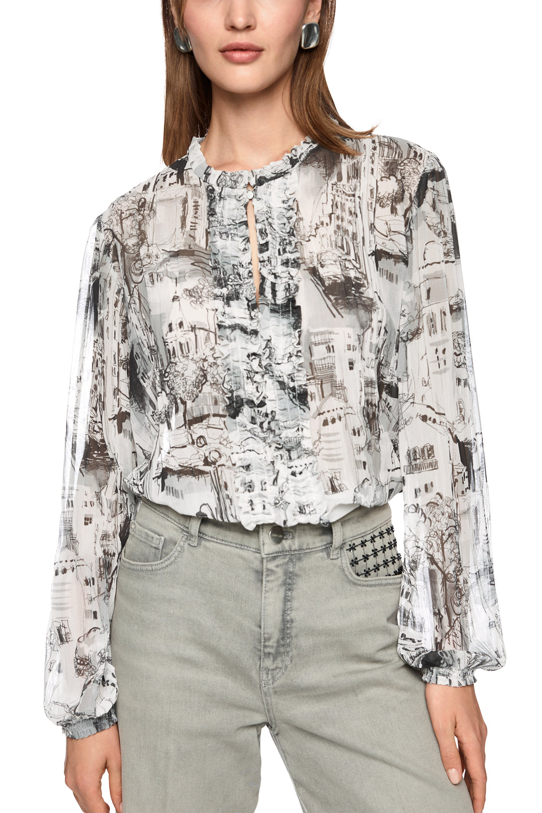 Woman wearing a patterned blouse and light jeans on a white background
