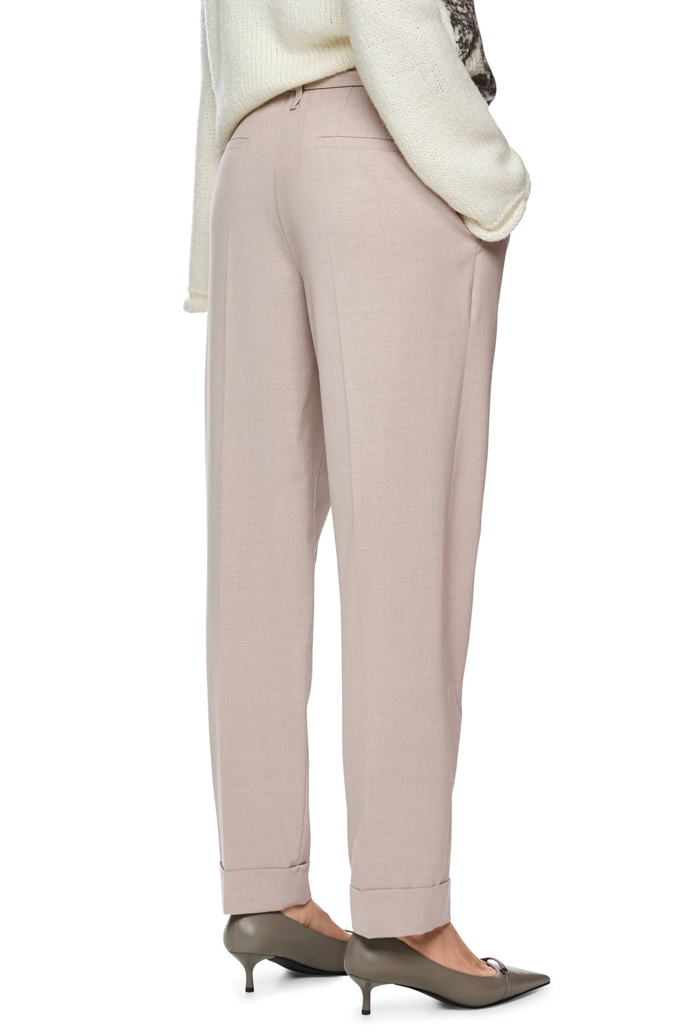 Beige pants worn with a white sweater on a white background