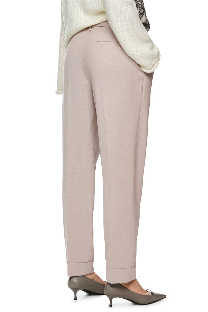 Beige pants worn with a white sweater on a white background