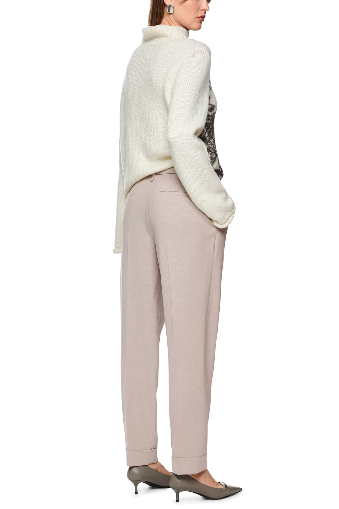 Woman wearing a white sweater and beige pants on a white background
