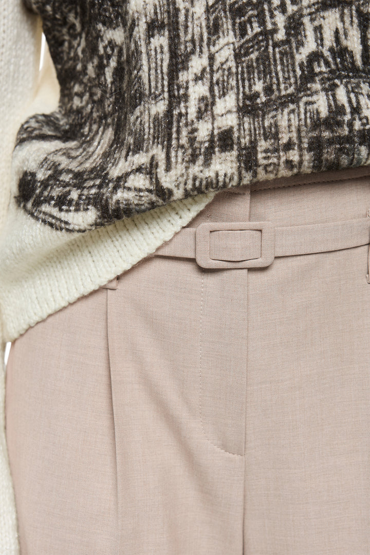 Close-up of a patterned sweater and beige pants with a belt.