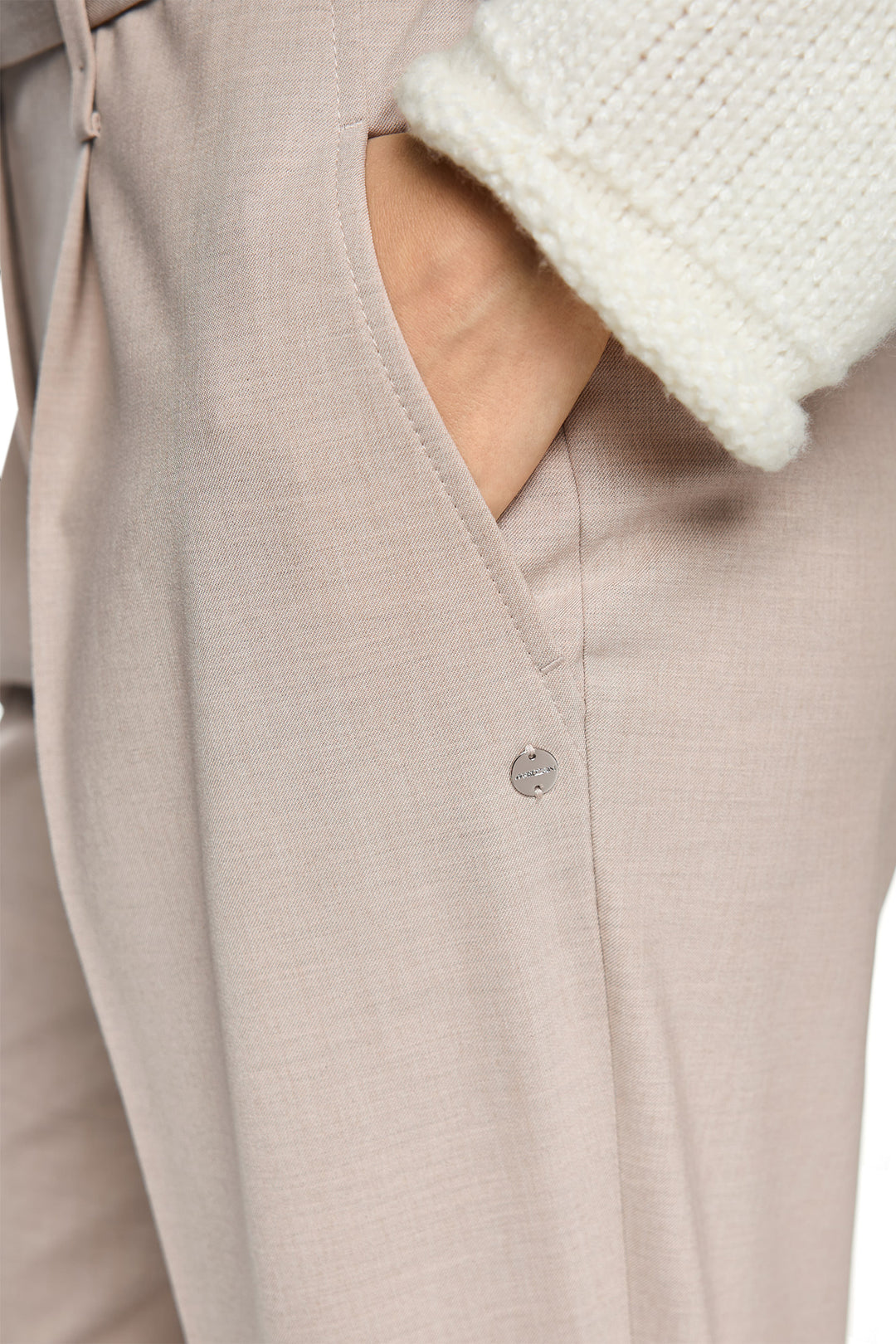 Close-up of a beige garment with white fur trim on a white background