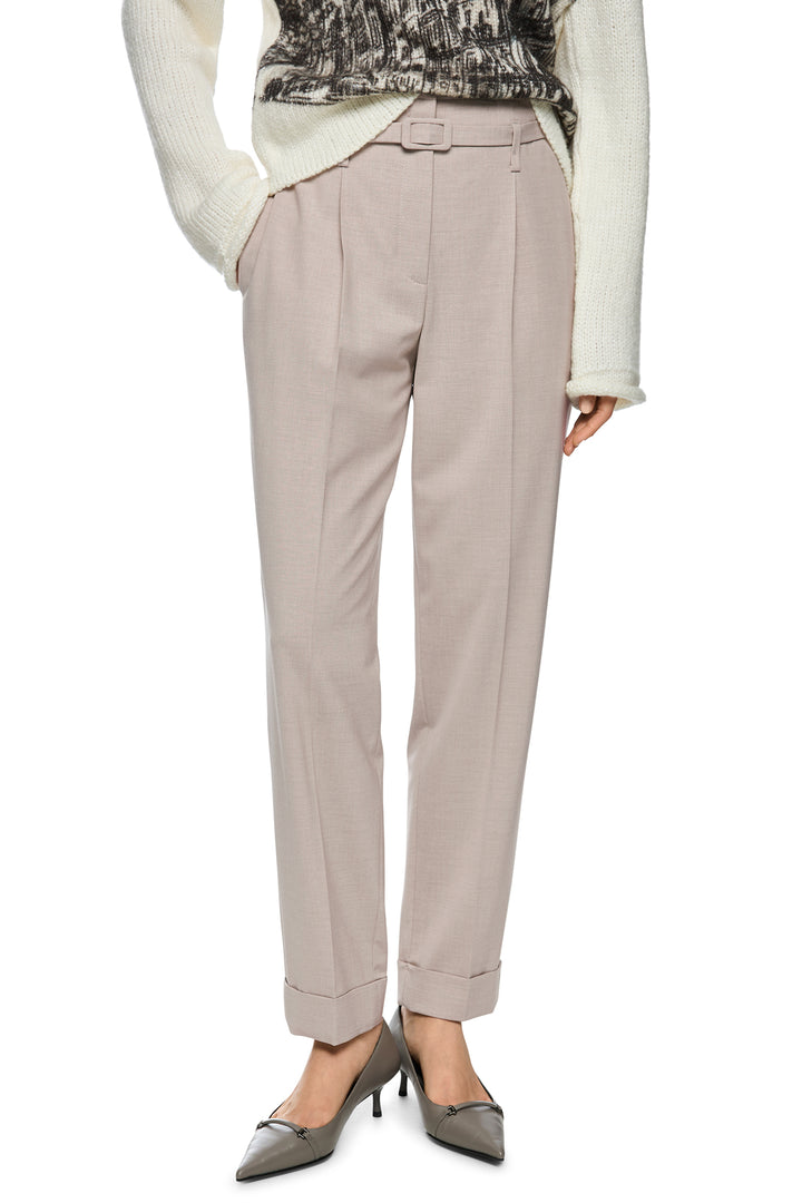 Beige pants worn with a white sweater and gray shoes on a white background