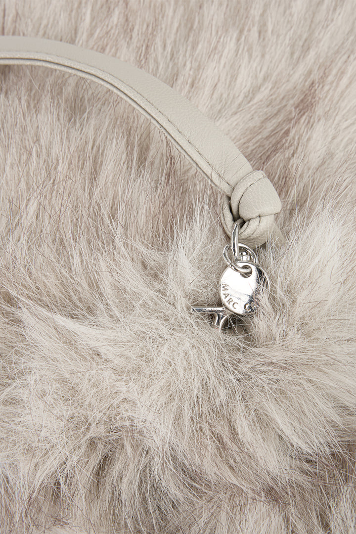Close-up of a beige strap with a heart-shaped charm on a fur surface