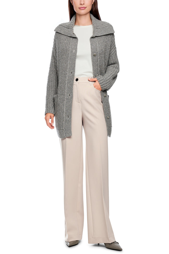 Person wearing a gray cardigan and beige pants on a white background