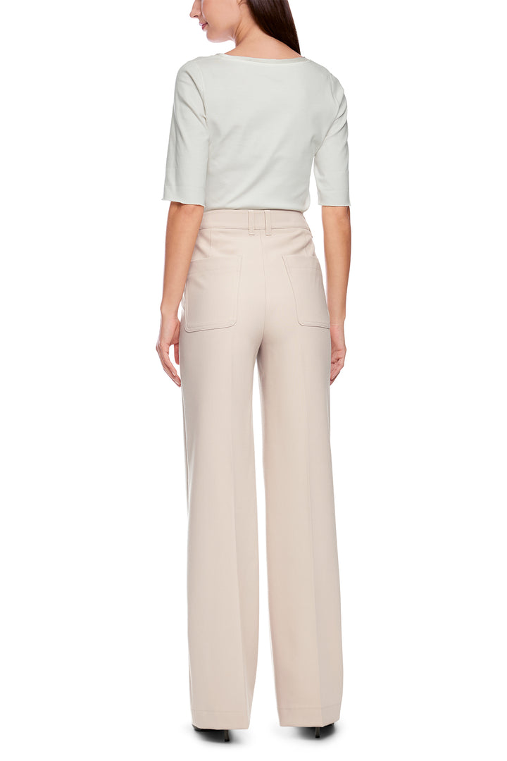 Woman wearing a light green top and beige pants on a white background