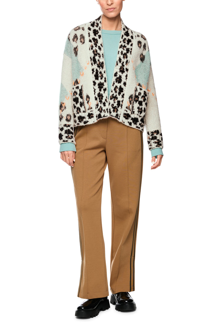 Person wearing a patterned shirt with a leopard print design, beige pants, and black shoes on a white background.