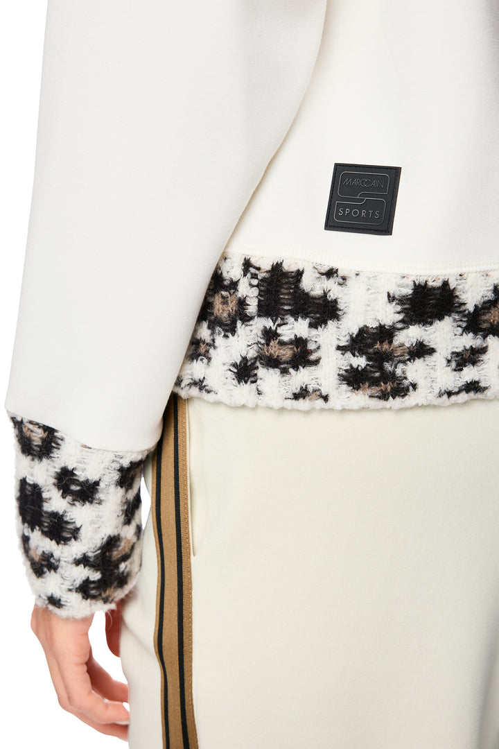 Close-up of a white coat with patterned cuffs and a visible brand label.
