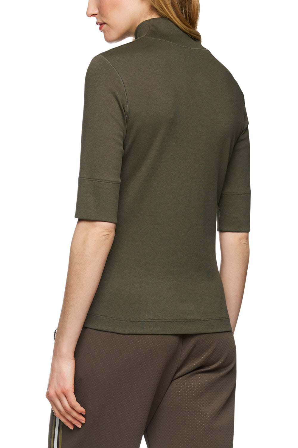 Person wearing an olive green zip-up top and brown pants on a white background