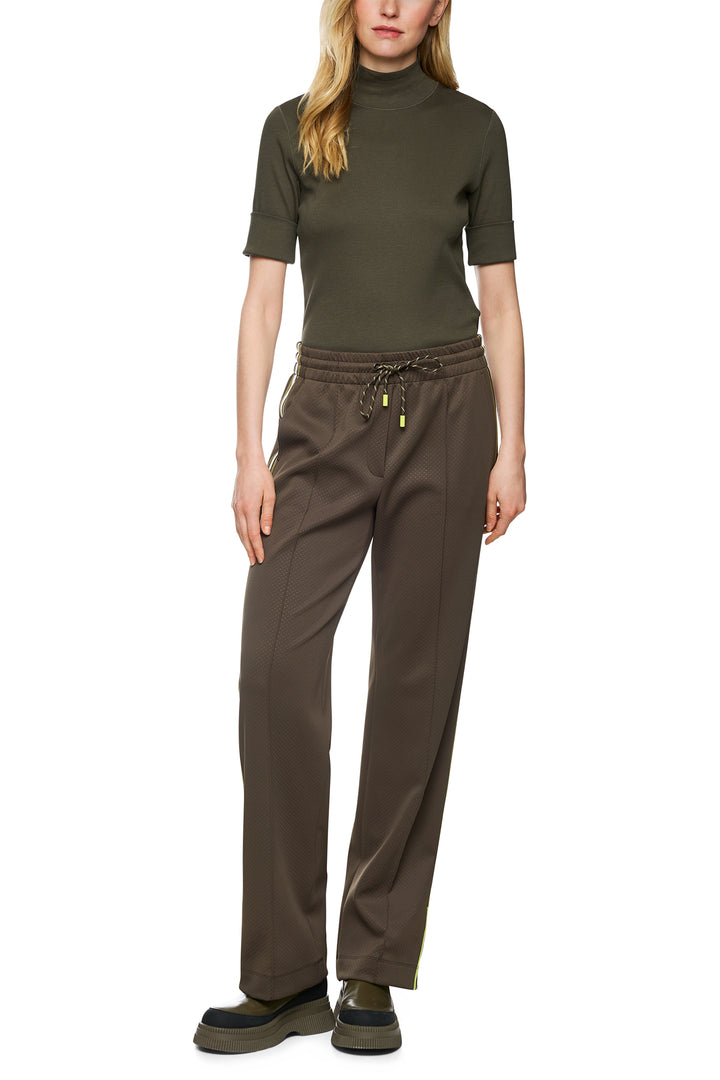 Woman wearing a green turtleneck and brown pants on a white background