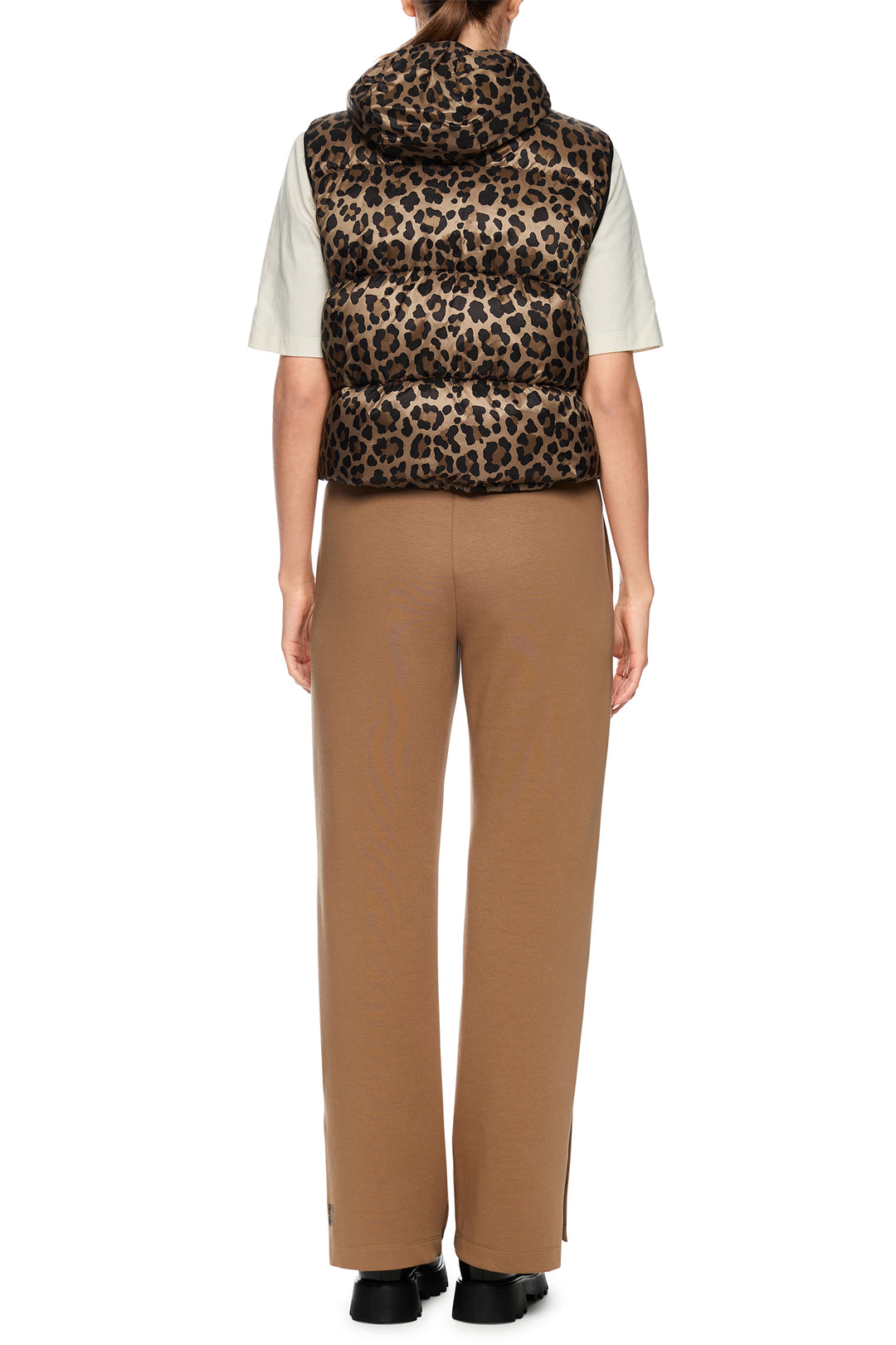 Person wearing a leopard print vest over a white shirt with beige pants on a white background