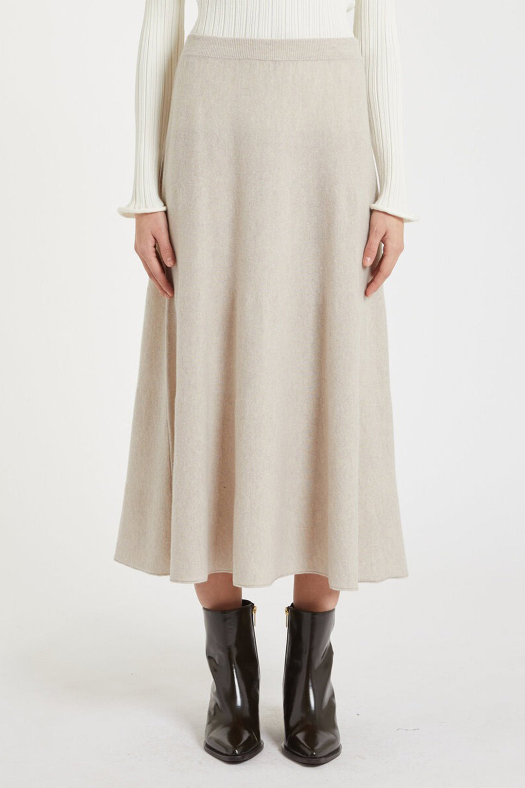 Person wearing a beige skirt and black boots on a white background