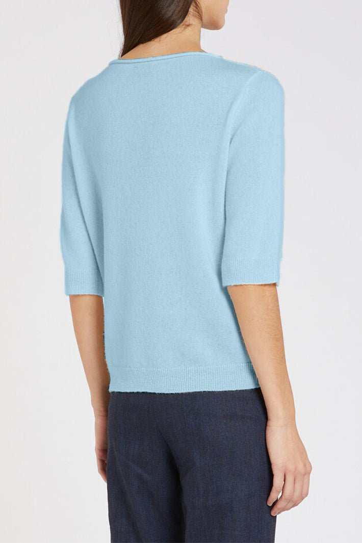 Light blue short-sleeve top worn by a person on a white background