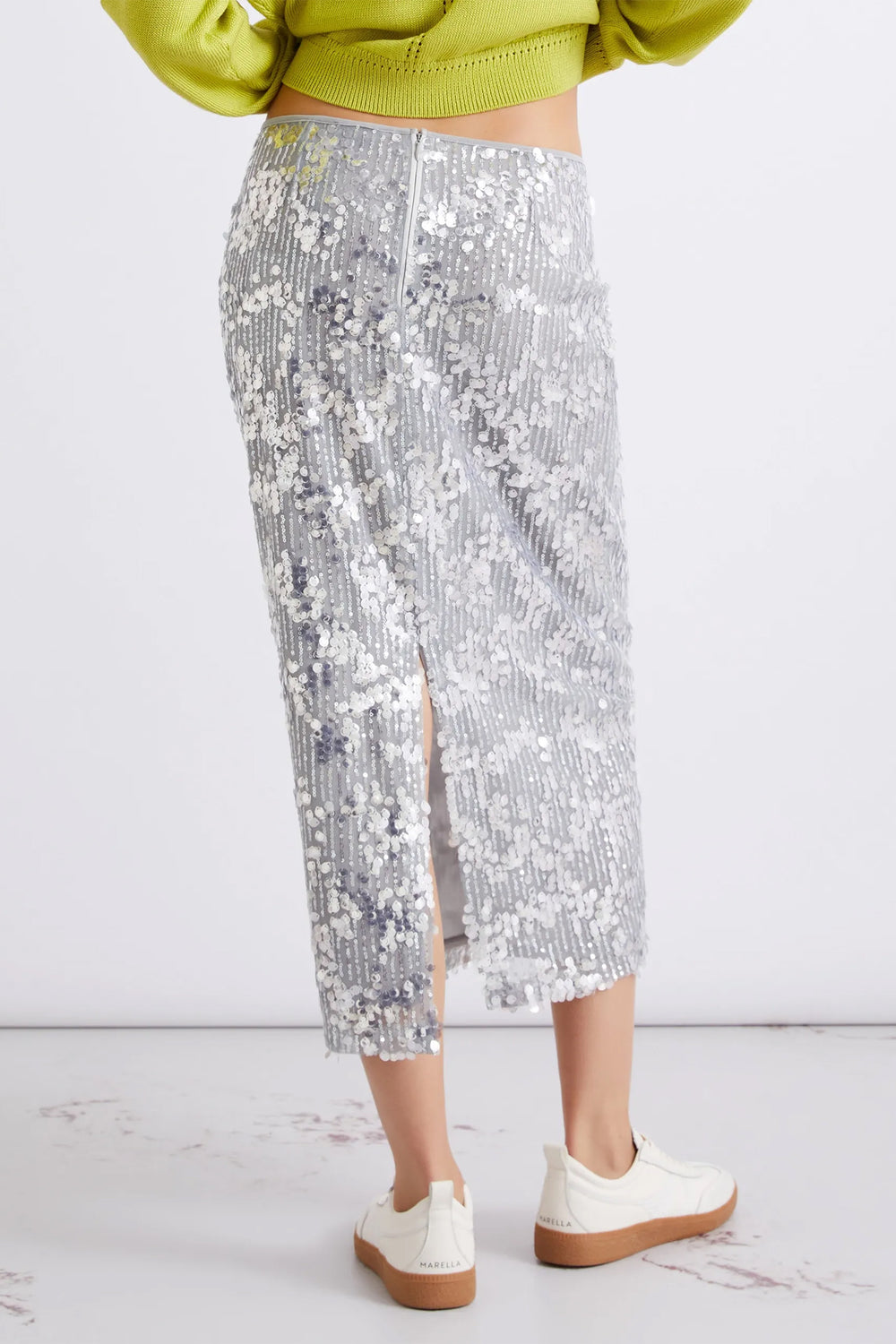 Person wearing a silver sequin skirt with a white background