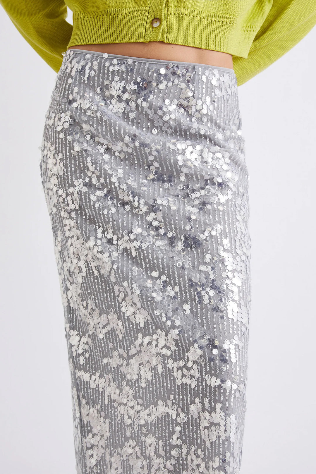 Silver sequin skirt worn with a green cropped top on a white background