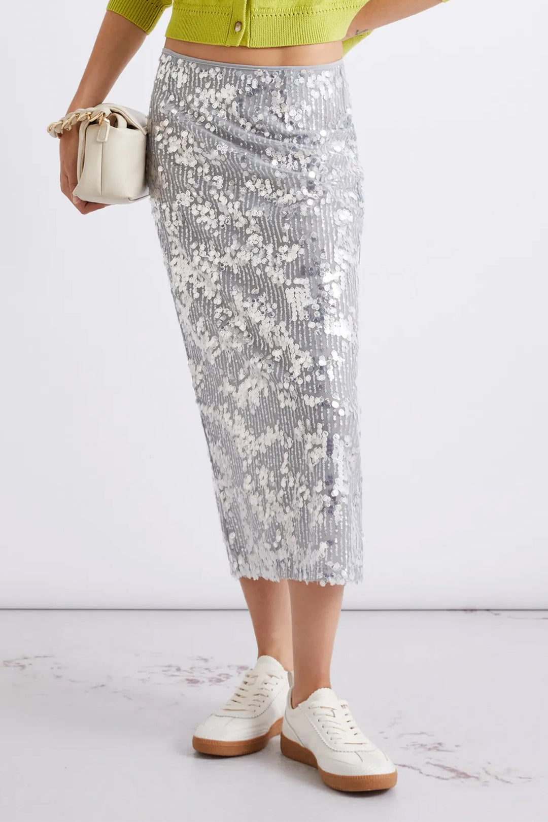 Person wearing a silver sequin skirt with a white background